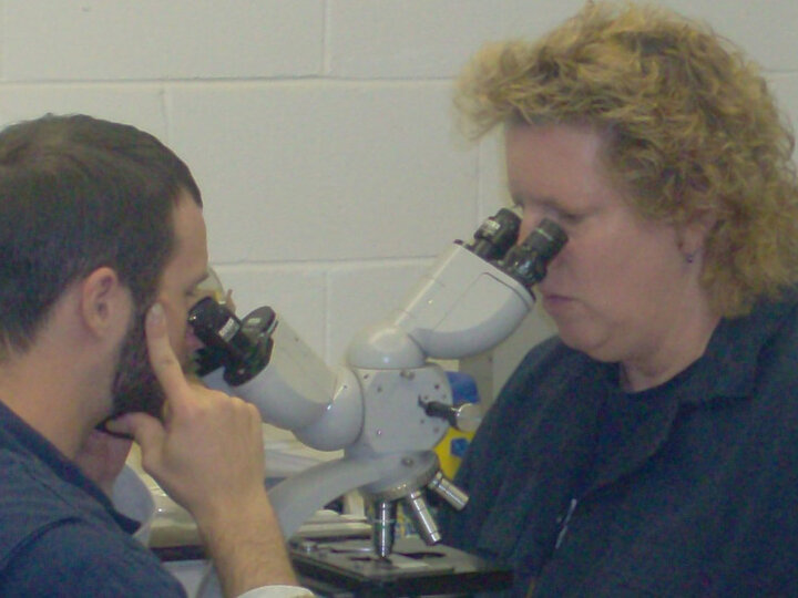Student and teacher looking in a microscope.